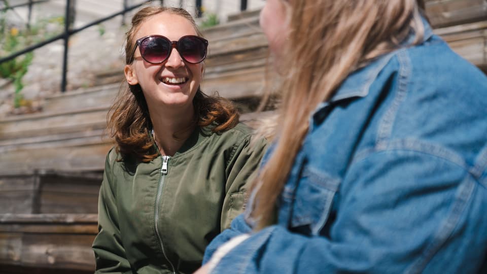Två studenter som sitter och pratar i en trappa. 
