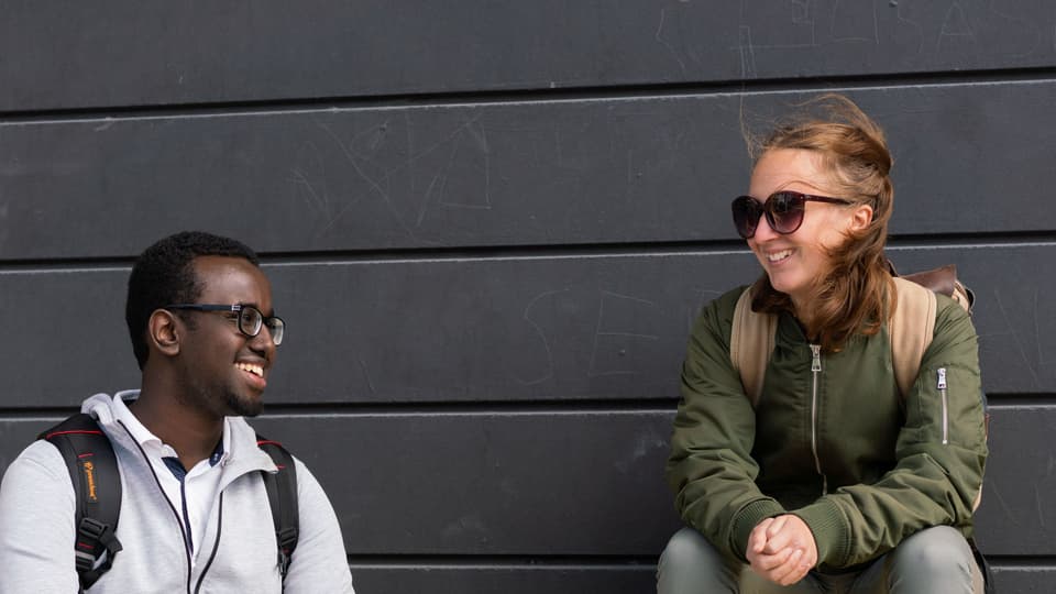 Two students sitting on a yellow bench.