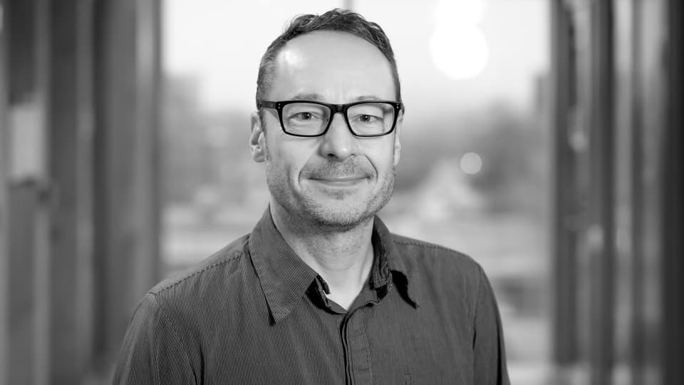 En bild i svartvitt på en man som tittar in i kameran.