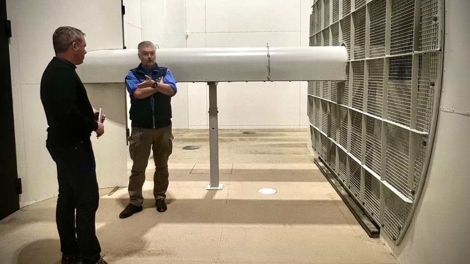 Två män står vid en stor fläkt.