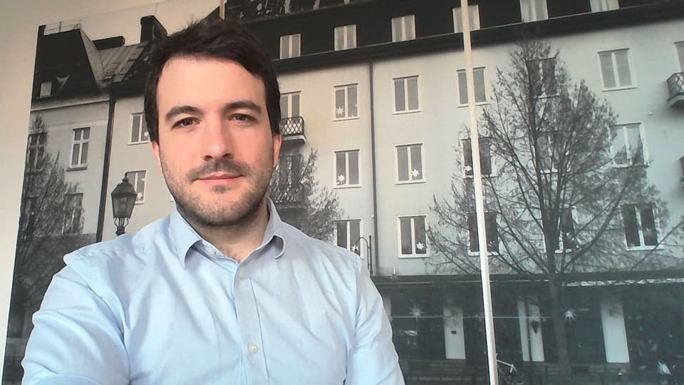 En man står framför ett stort fotografi av en husfasad.