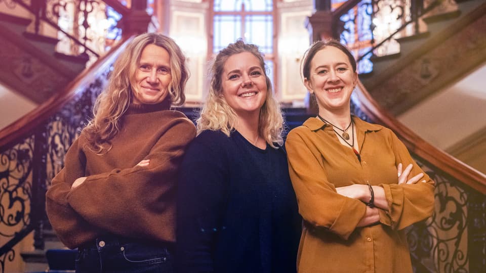 Tre kvinnor framför en trappa