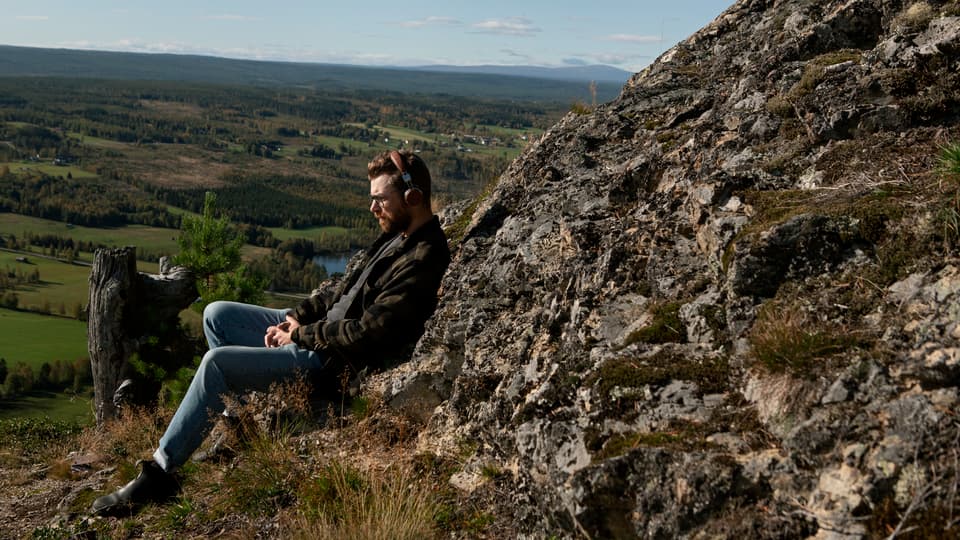 Man lutar sig mot bergvägg och blickar ut över öppet landskap