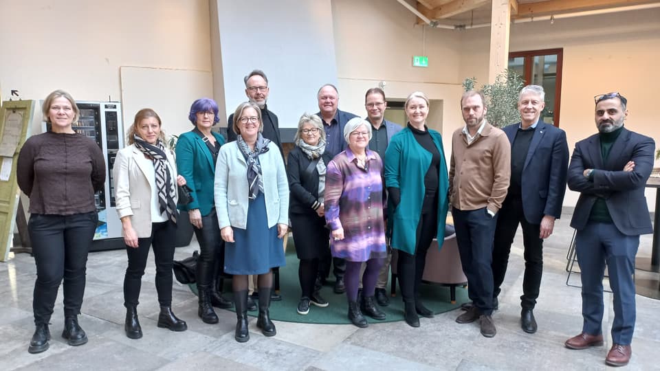 Tretton personer står uppställda för en gruppbild.