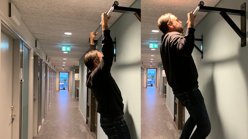 Man som häver sig upp på en chinstång i en korridor.