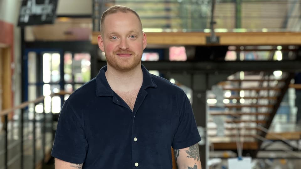 En man med mörk tshirt och tatueringar står i ett trapphus