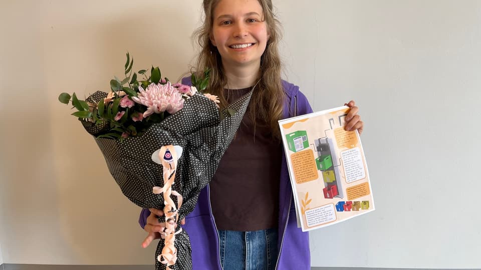 En gad tjej i lila jacka och jeans som håller en bukett med blommor och ett papper med en illustration på