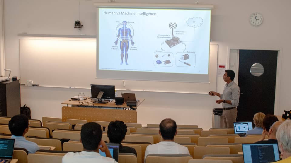 En man står framför åhörare och håller en presentation.