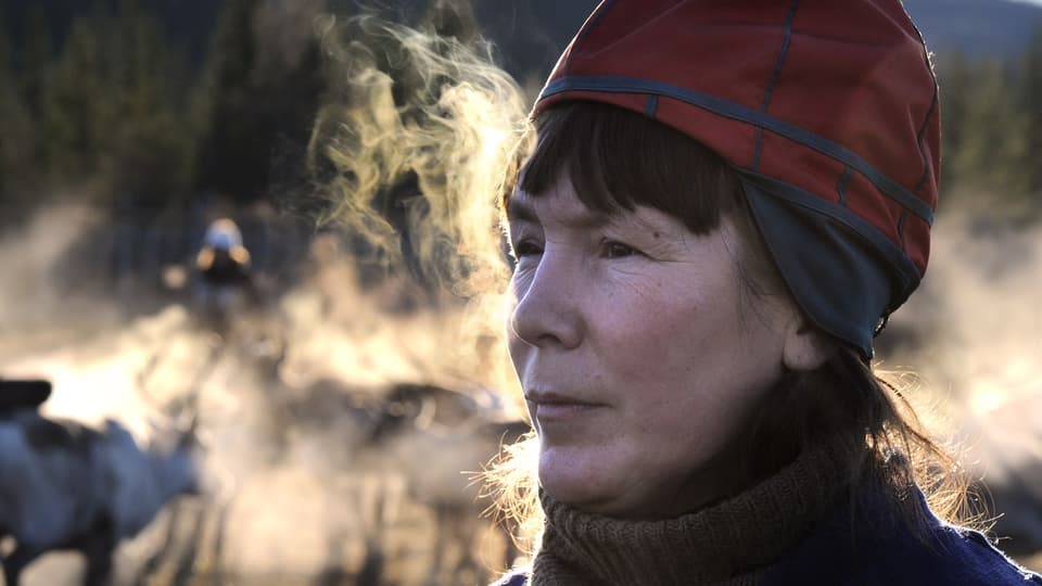 Kvinna i sydsamisk kvinnomössa andas så det bildas imma runt henne.