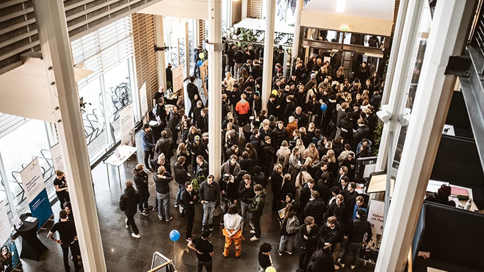 En stor grupp elever står på insidan av ingången till Ljushallen. 