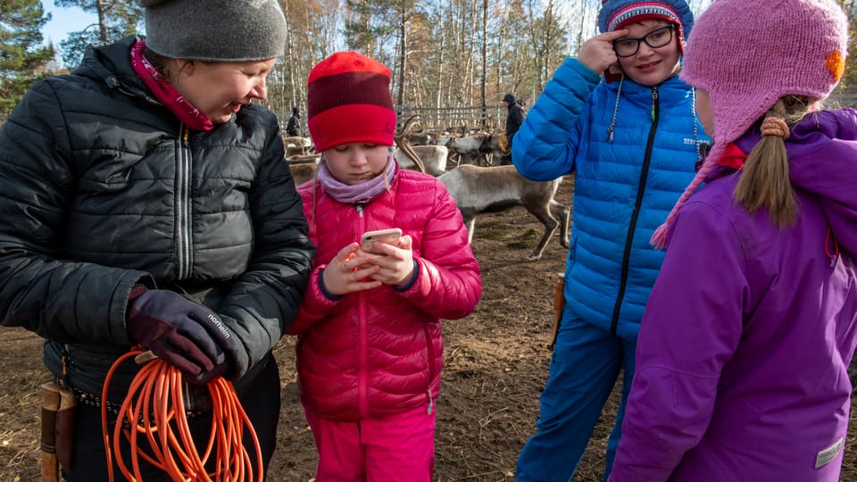 En flicka visar något på sin mobil för en kvinna.