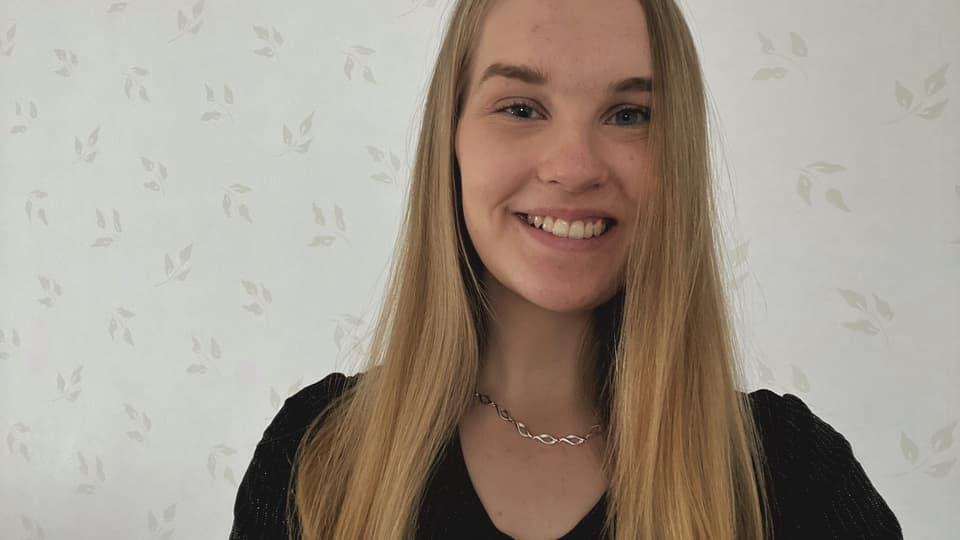Ljushårig kvinna framför en ljus men mönstrad tapet