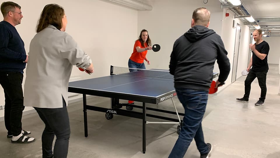 Flera personer spelar rundpingis i källarlokal.