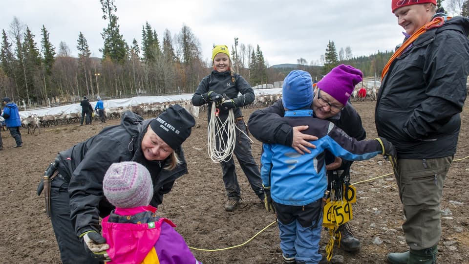 Några kvinnor och barn utanför ett rengärde.