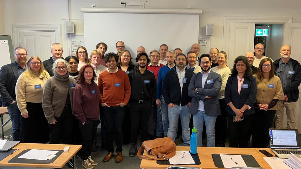 En grupp personer står tillsammans framför en whiteboardtavla.