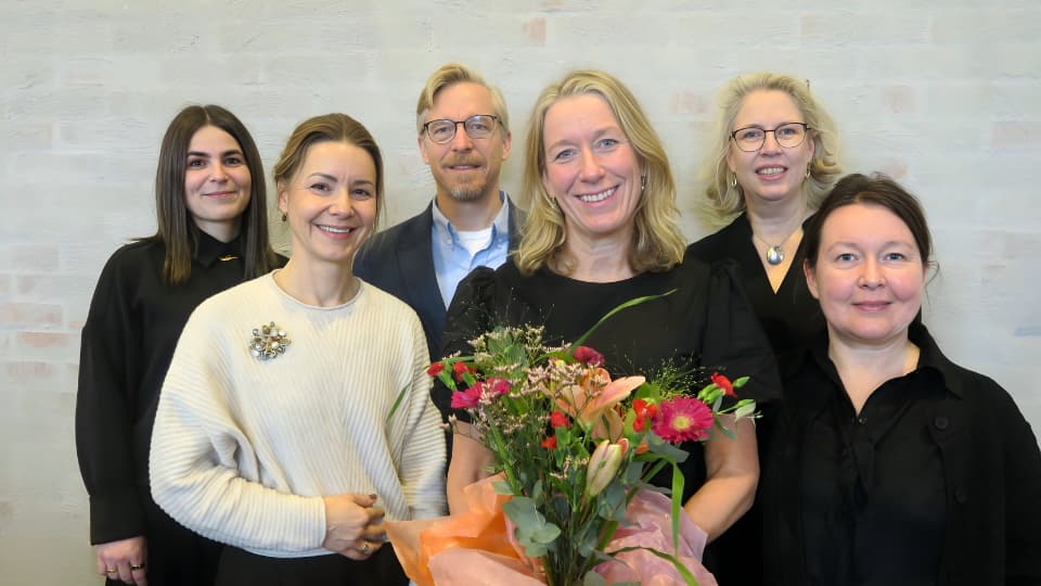 En grupp med sex forskare står framför en vägg i en lärosal