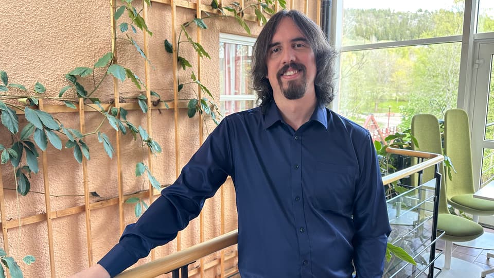 A man with a blue shirt and long brown hair