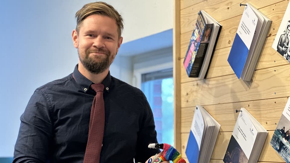 En man med blå skjorta och röd slips håller en hammare