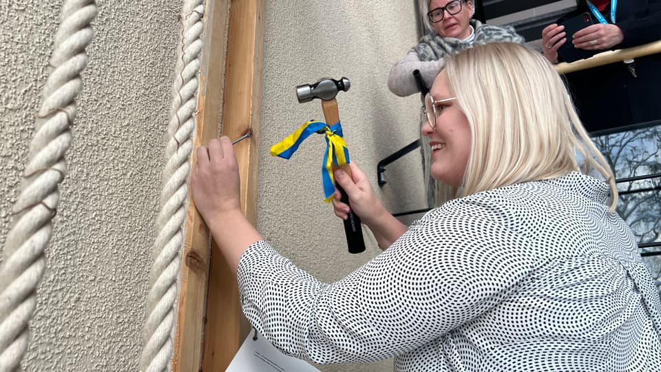 En kvinna som hamrar in en spik i en vägg