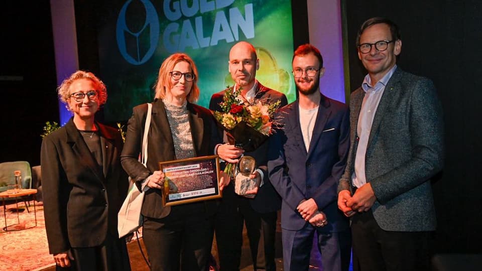 Tre män och två kvinnor med diplom och blommor i samband med prisutdelning