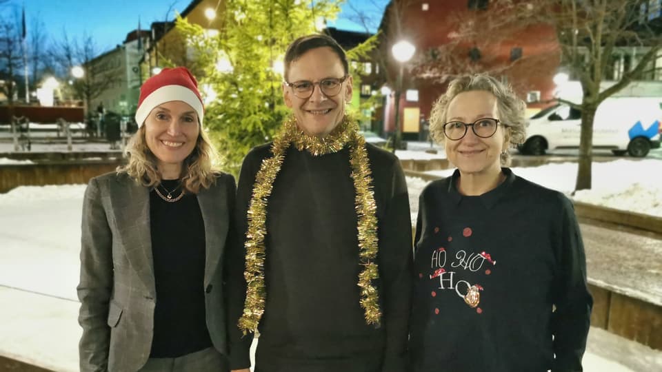 En man och två kvinnor i julglitter utomhus.