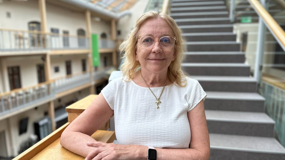 Porträttfoto av en blond kvinna ståendes framför en trappa