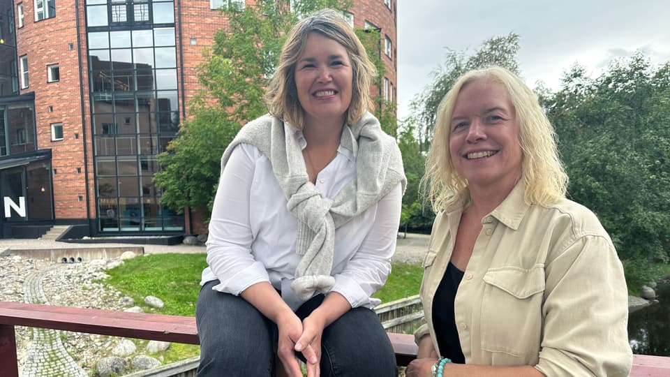 två leede kvinnor framför ett staket
