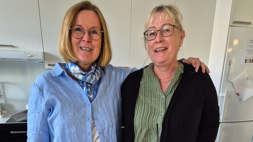 Två kvinnor ler in i kameran