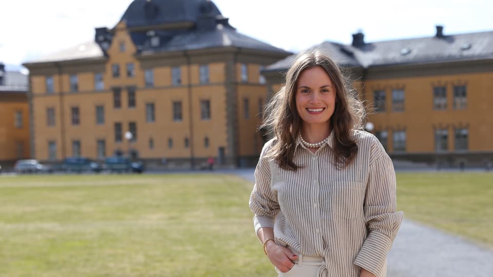 Kvinna utomhus med byggnader i bakgrunden.