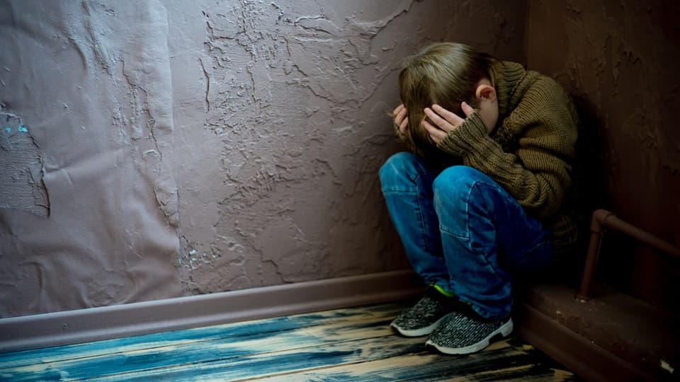 Pojke sitter uppkrupen i hörnet av ett rum