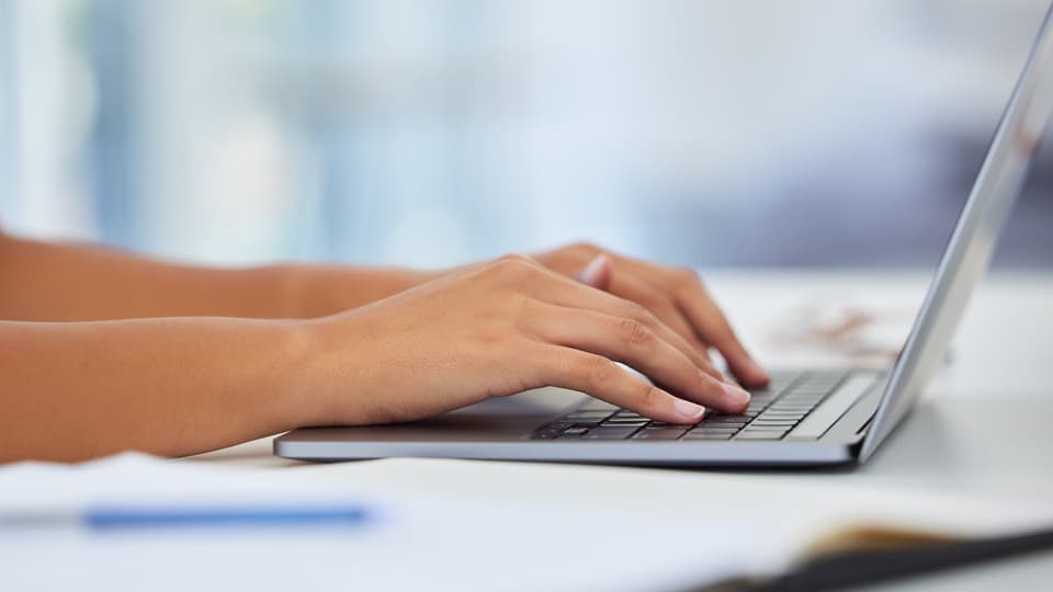 Två händer om skriver på en laptop