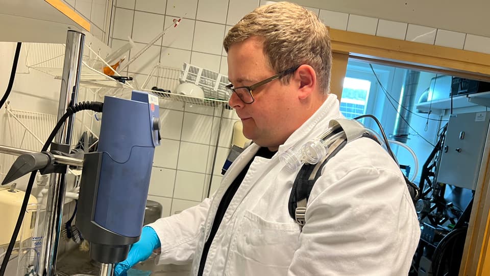 En man i vit laboratorierock arbetar i ett laboratorium.