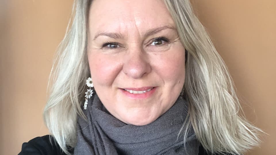 Ett porträttfoto av en blond kvinna mot en ljusbeige bakgrund