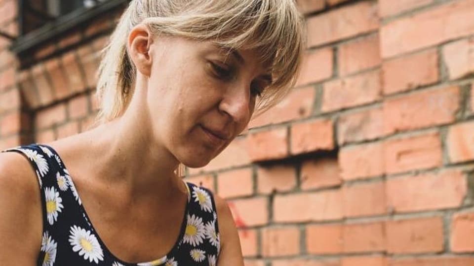 Olga Milinchuk sitter på en uteservering och skriver på sin telefon