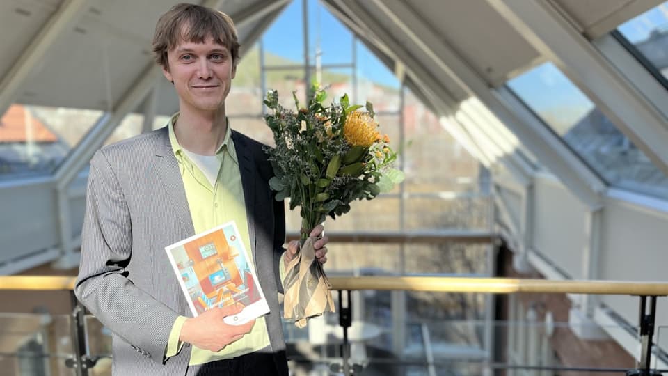 Man med en blomma i ena handen och ett diplom i den andra. 