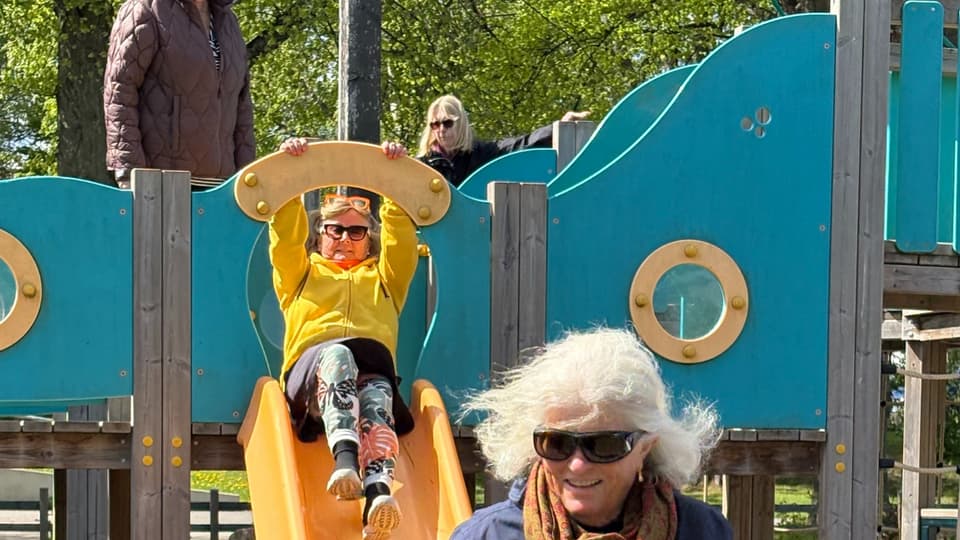 Äldre kvinnor åker rutschkana på lekplats.