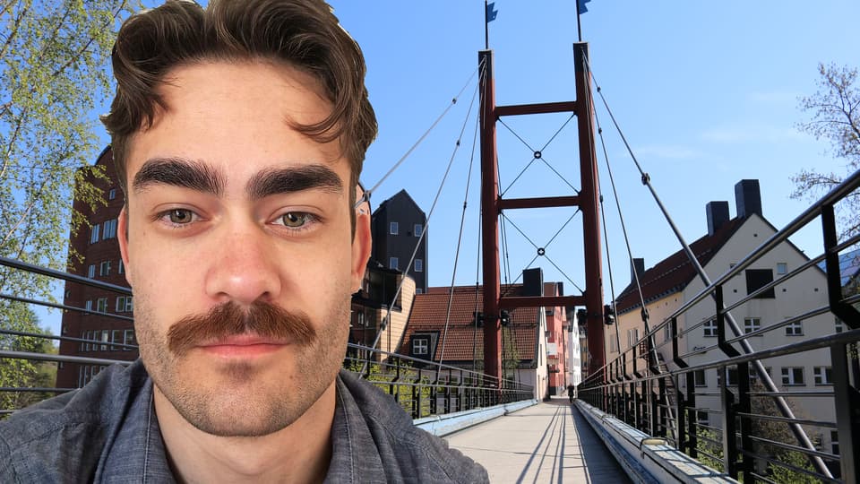 Porträtt av en man med mustasch, i bakgrunden en bro samt byggnader