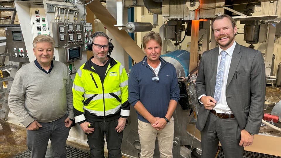 Fyra män står tillsammans i en industrilokal