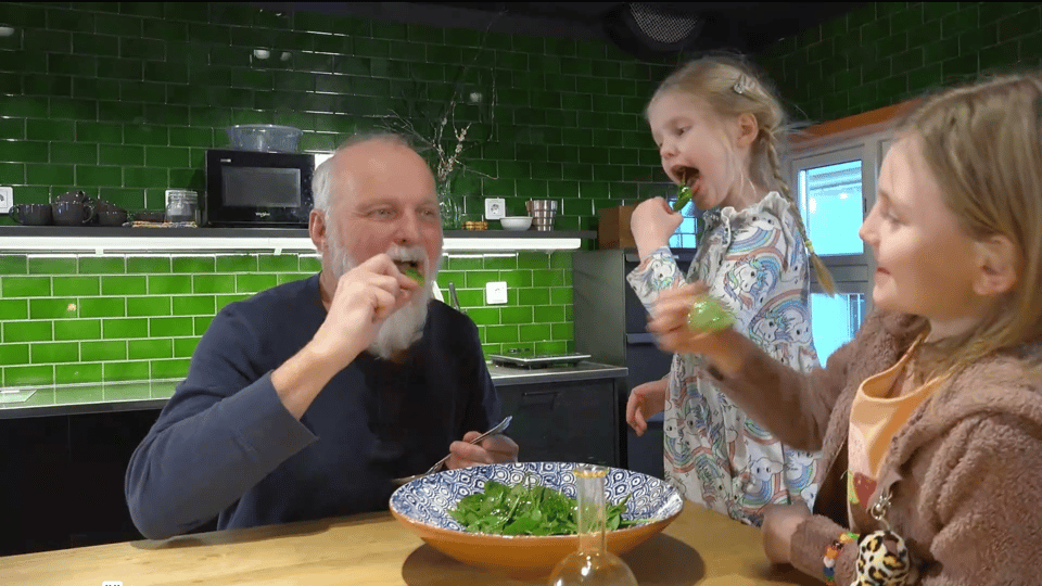 En man och två barn äter sallad