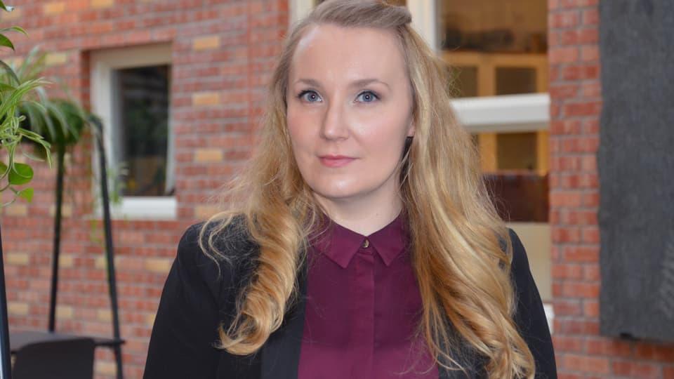 Kvinna med långt hår, vinröd blus och svart kavaj