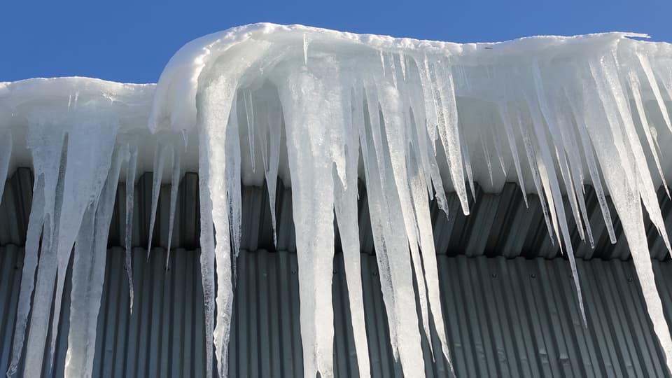 Snö och istappar hänger från tak