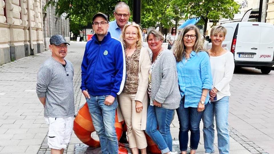 En grupp med människor står tillsammans och tittar mot kameran.