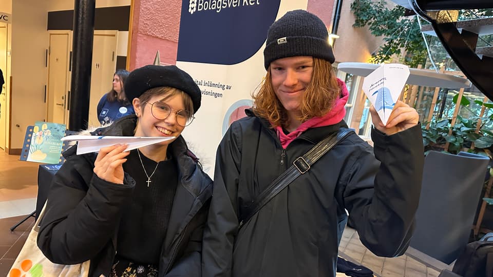 Två unga personer med varsitt pappersflygplan
