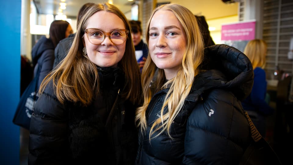 Two young women are standing together looking at the camera.