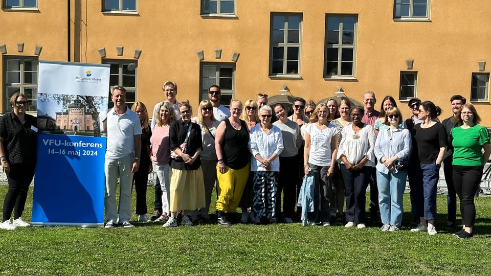 Gruppbild på gräsplan framför ett gult hus.