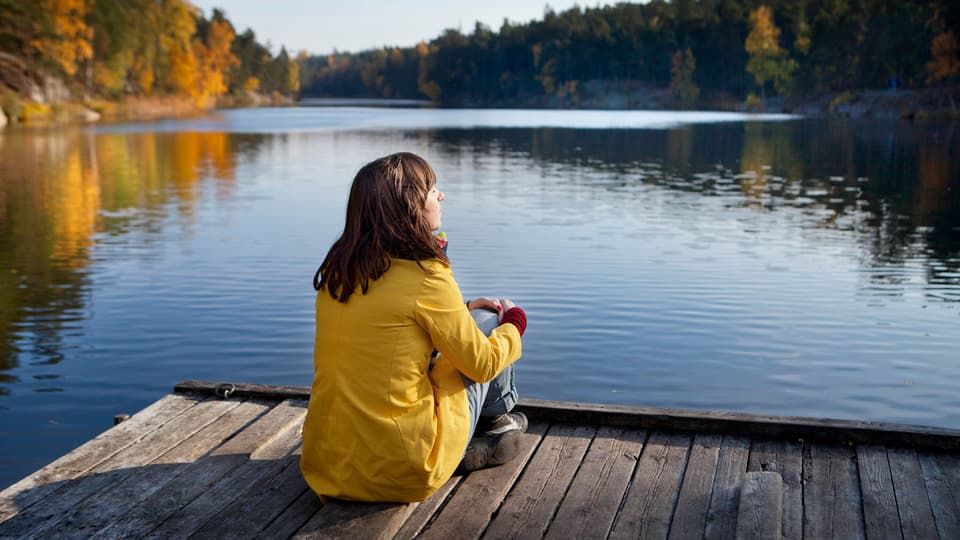 naturturist - en kvinna som sitter på en brygga.