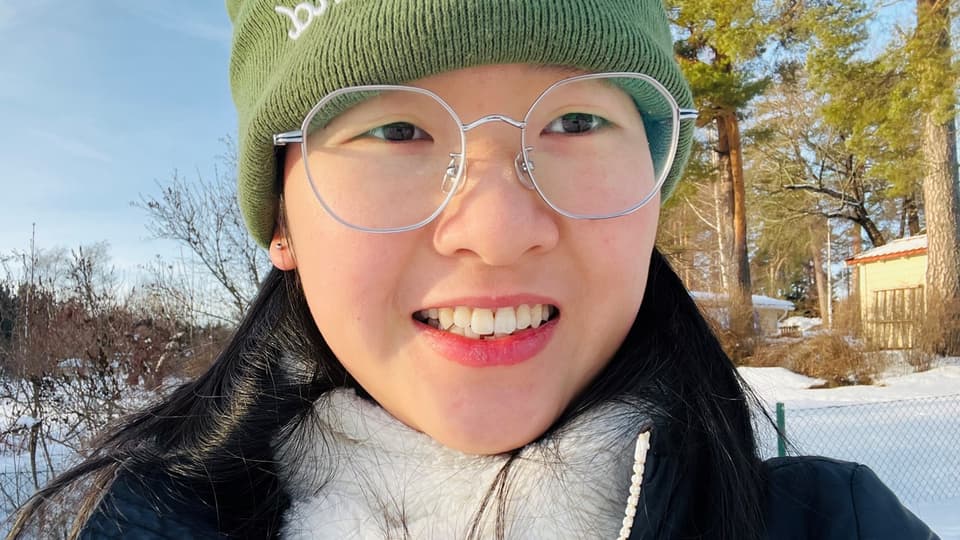  A woman in a winter landscape with trees and snow in the background.