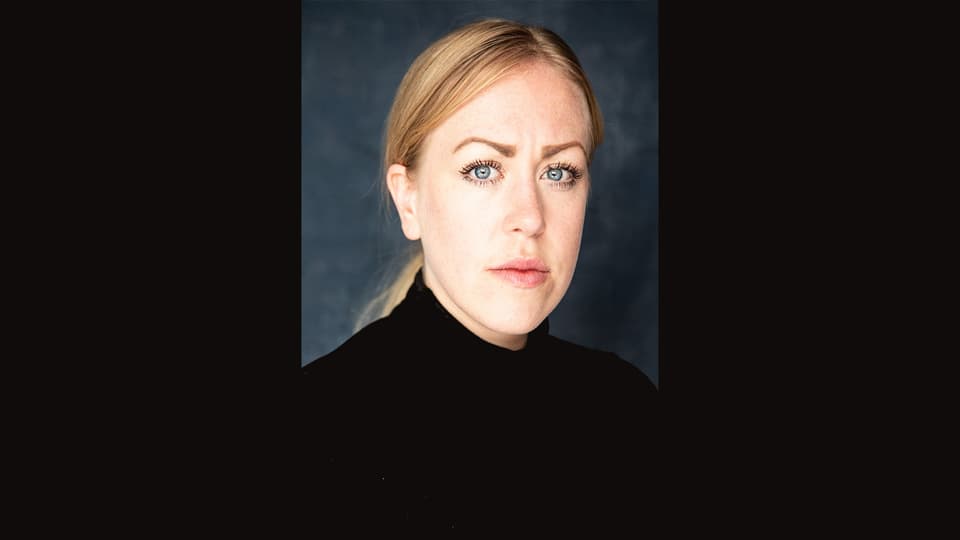 Ett porträttfoto av en blond kvinna mot svart bakgrund