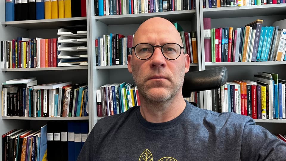 Jimmy Jaldemark framför en bokhylla med böcker