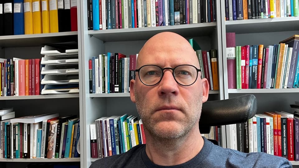 Jimmy Jaldemark framför en bokhylla med böcker